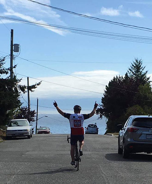 Jarek Bekesza cycling with arms raised